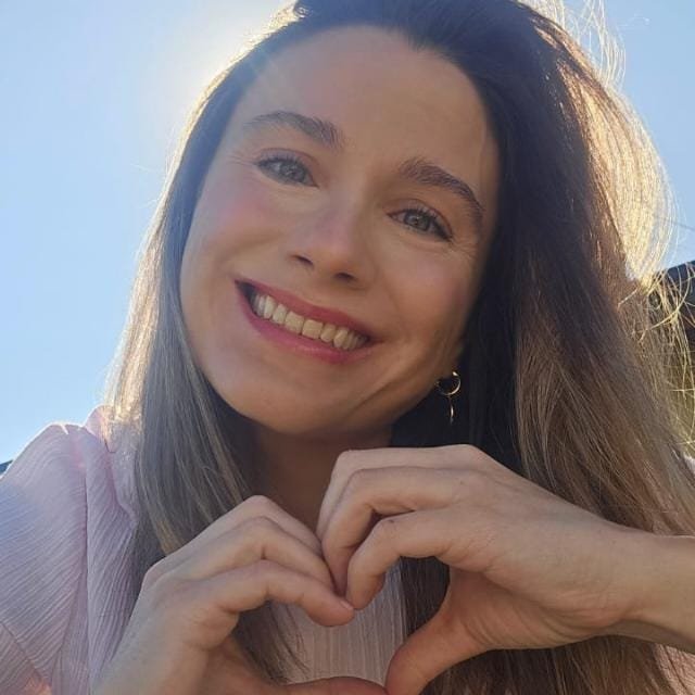 Maca sonriendo y formando un corazón con las manos